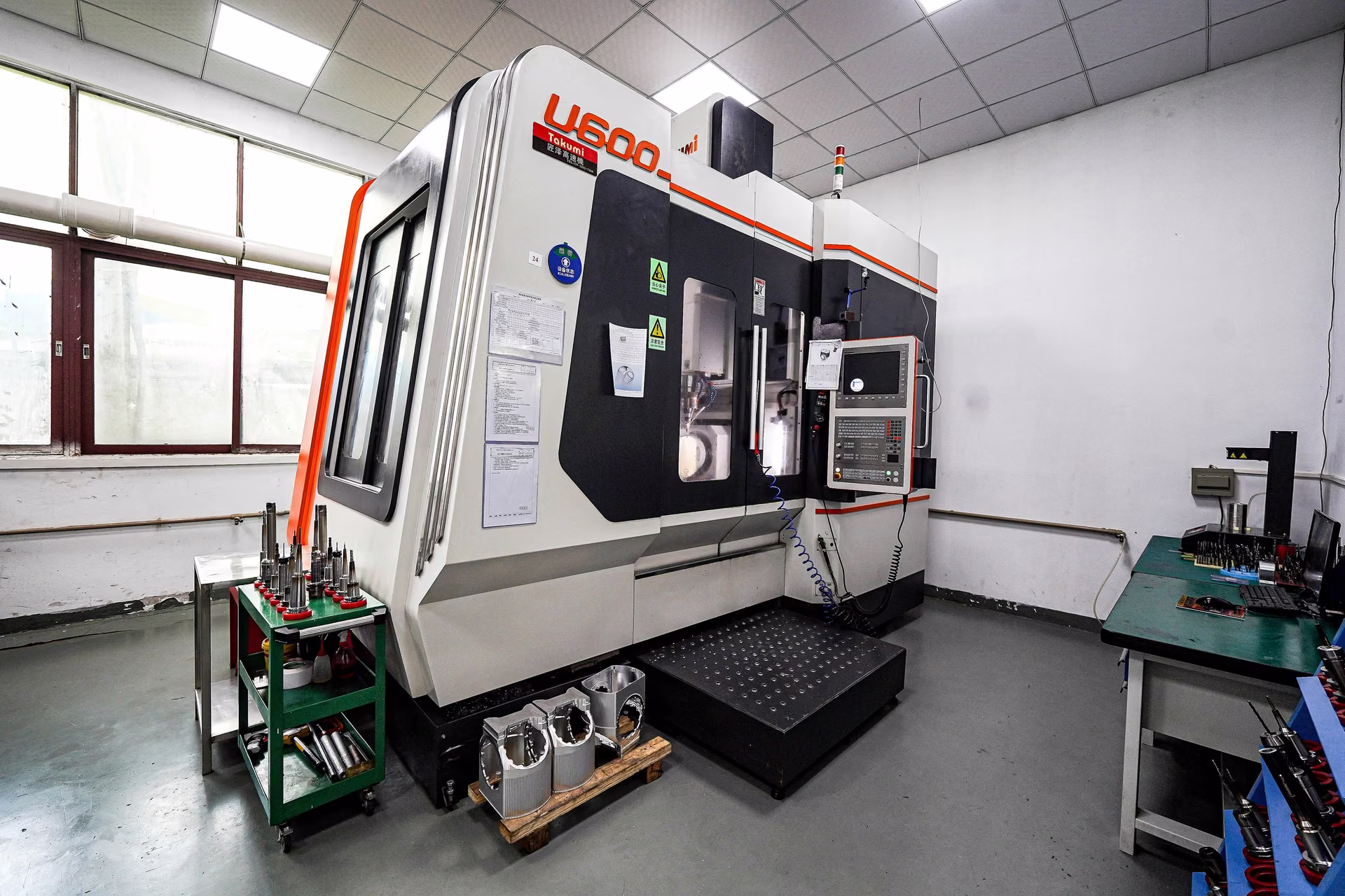 Five-axis CNC machining center and supporting equipment in an engineering-focused production cell