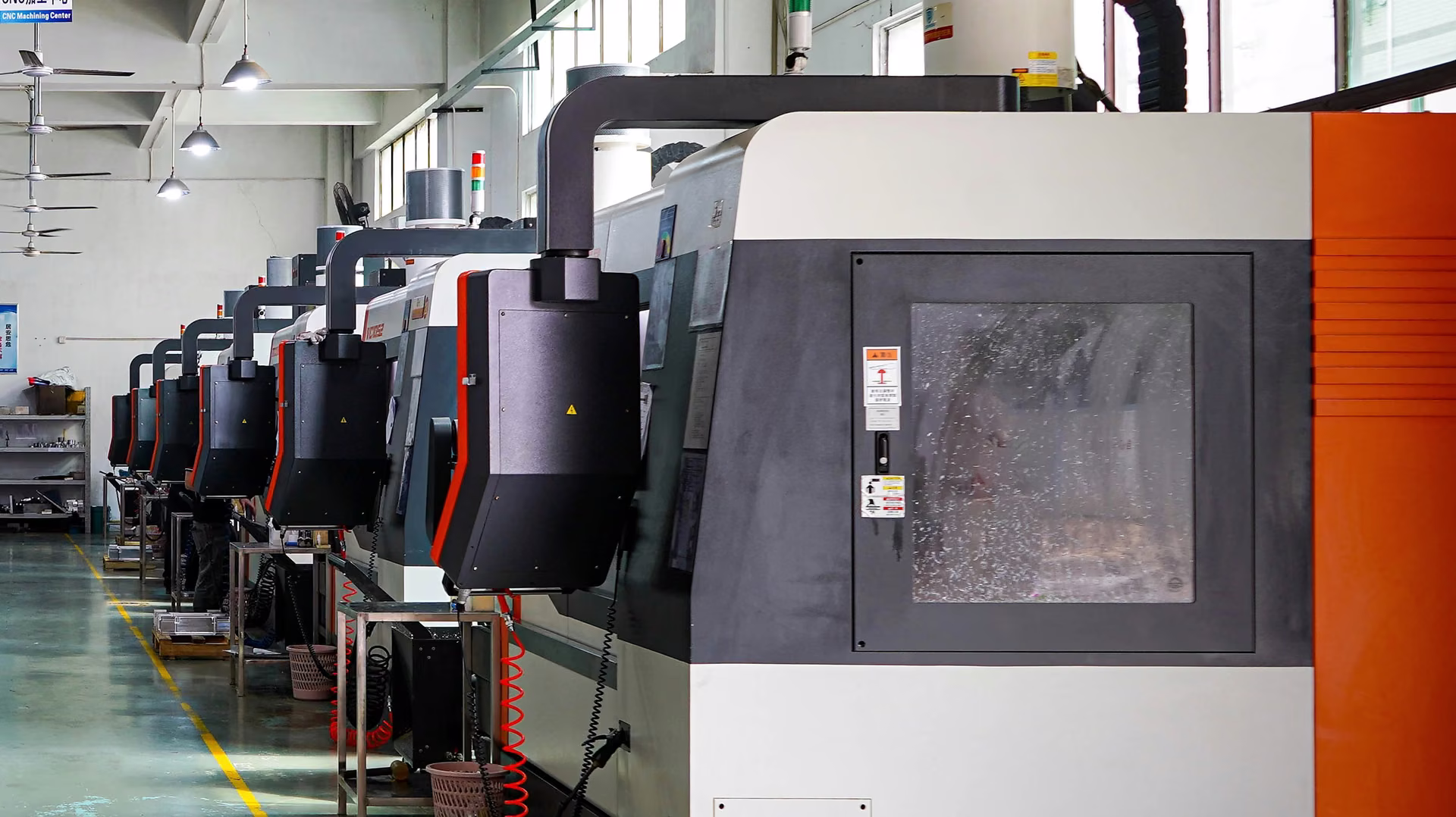 CNC production aisle with enclosed machine tools and an unobstructed view of the manufacturing floor