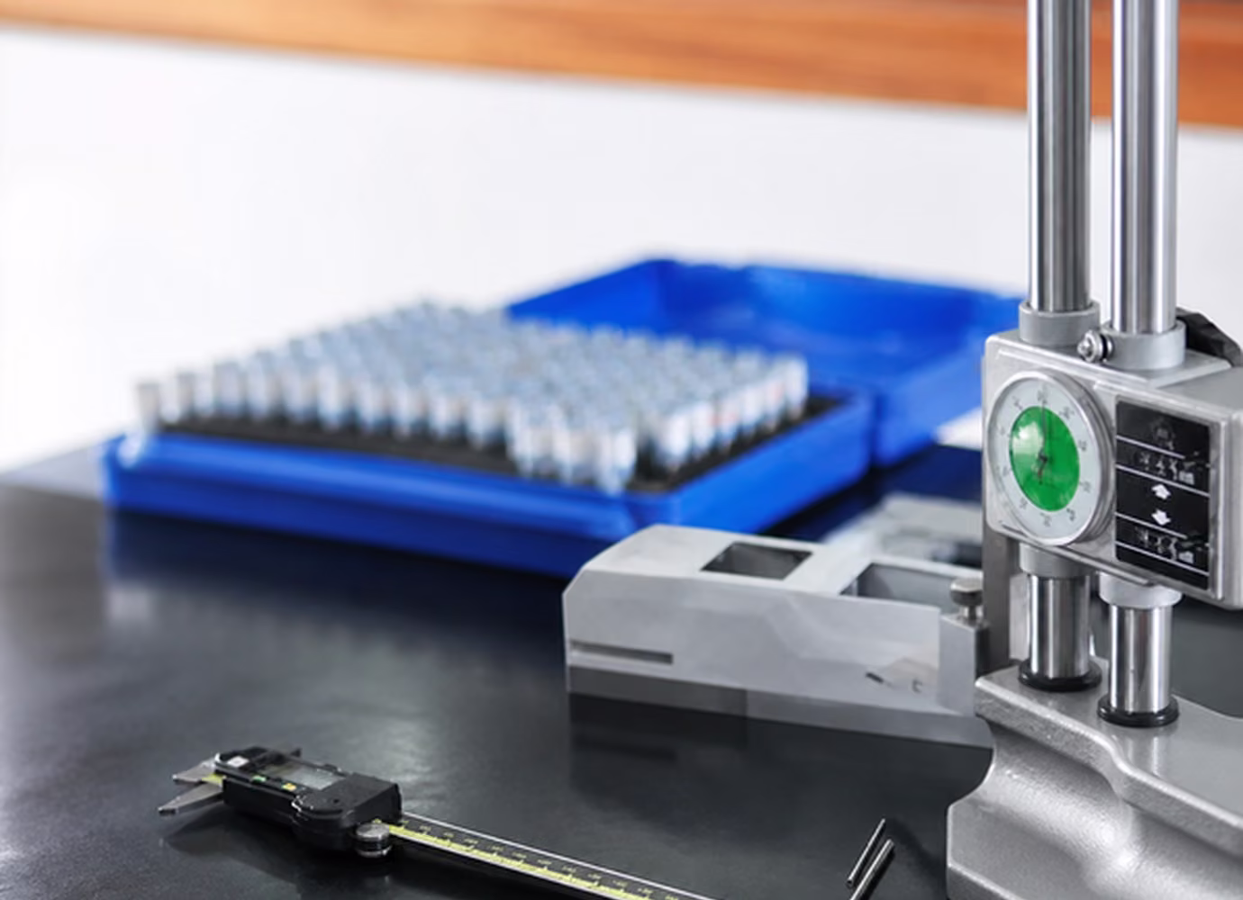 Bench gauges and measurement tools set up beside a batch of small production components