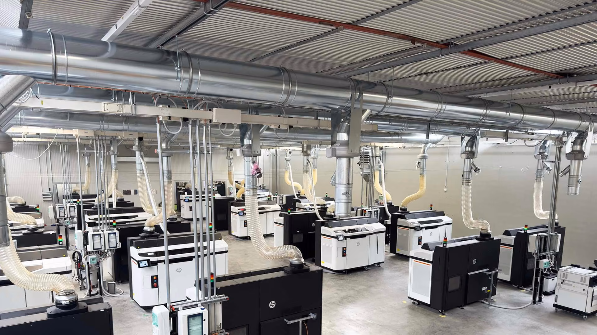 Rows of additive manufacturing systems arranged across an industrial production room