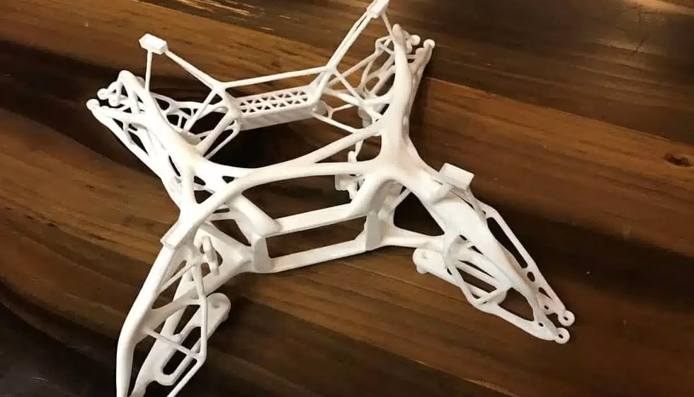 White additively manufactured nylon frame with lattice reinforcement on a wooden workshop surface