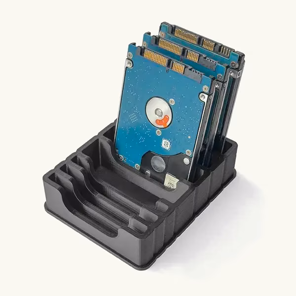 Black additively manufactured ESD storage fixture holding a compact hard disk drive upright.