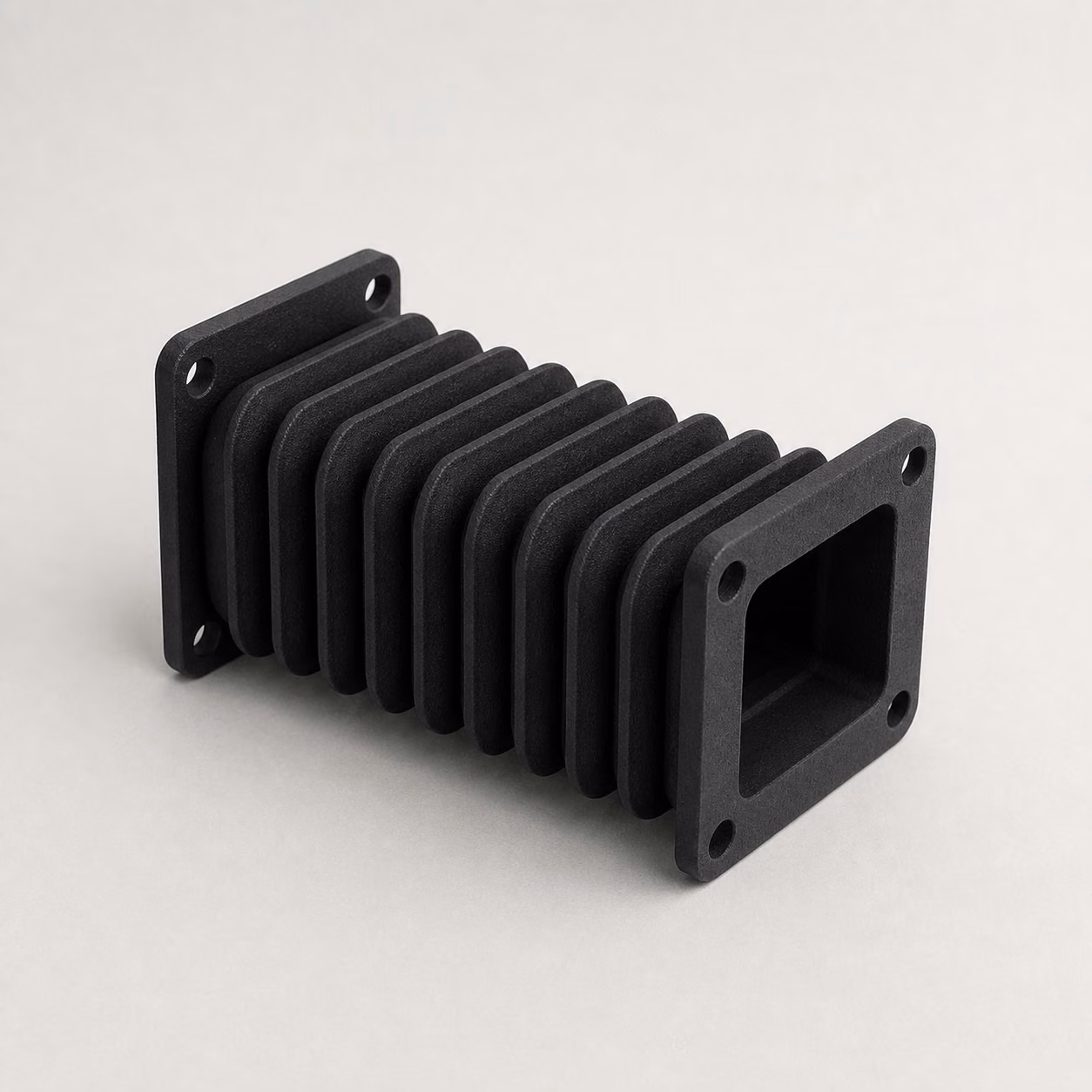 Black MJF TPU protective bellows with flexible accordion folds, end flanges, and mounting holes.