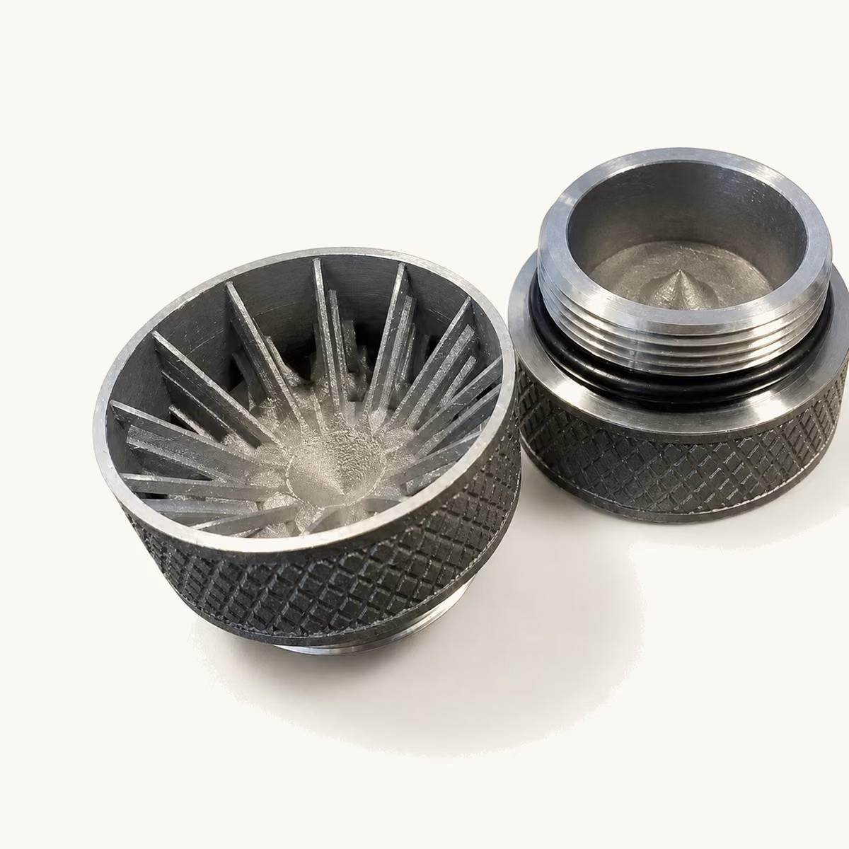 Metal-printed turbine component with closely spaced curved vanes beside a finished cylindrical metal part.