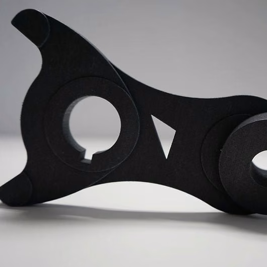 Black SLS structural bracket with curved profiles, circular interfaces, and weight-relief openings.