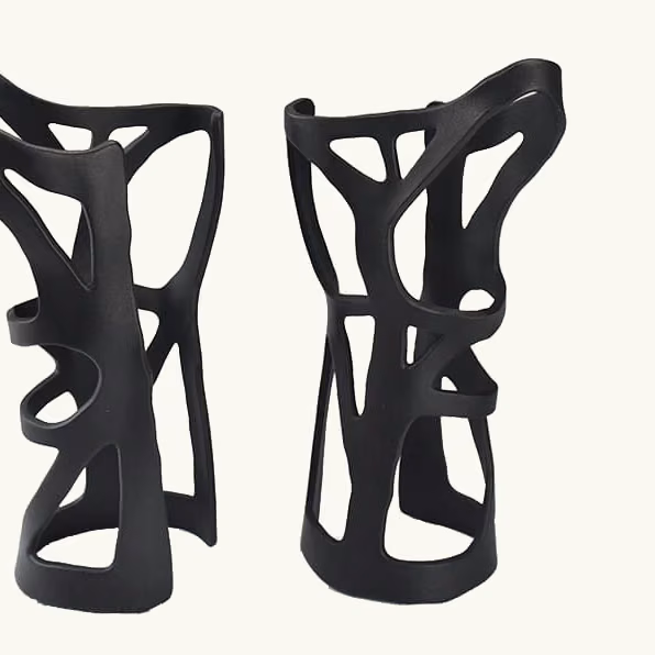 Pair of black topology-optimized additively manufactured supports with open structural ribs.