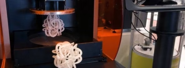 Stereolithography printer build chamber with small white resin parts suspended above the build platform