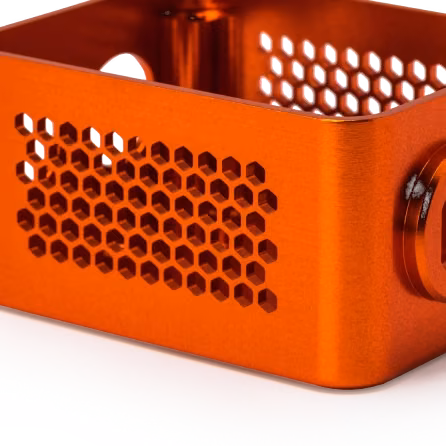 Orange anodized machined aluminum electronics enclosure with ventilation holes and finished mounting features.