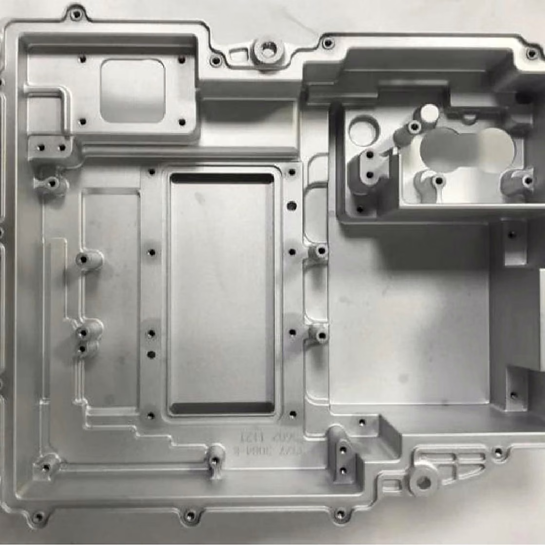 Large machined aluminum equipment housing with deep pockets, stepped cavities, bosses, and perimeter mounting holes.