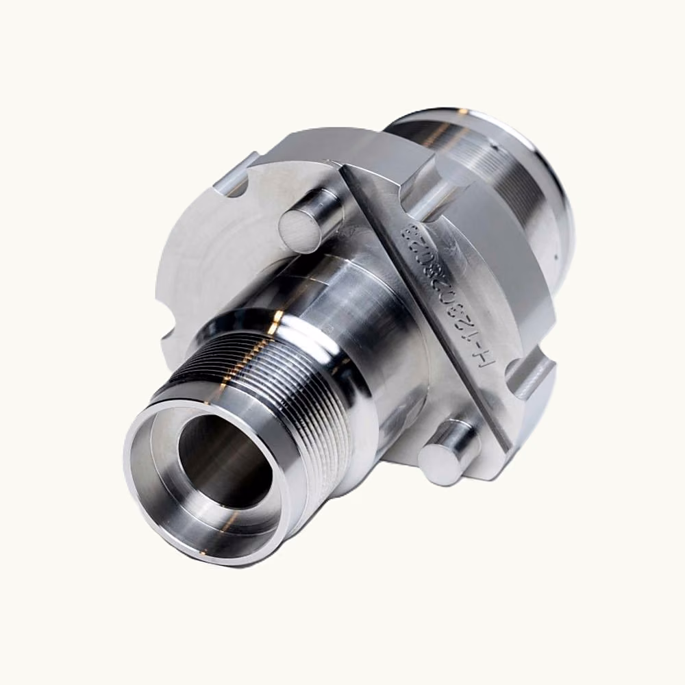 Machined stainless steel connector with a through bore, external thread, and flanged mounting features.