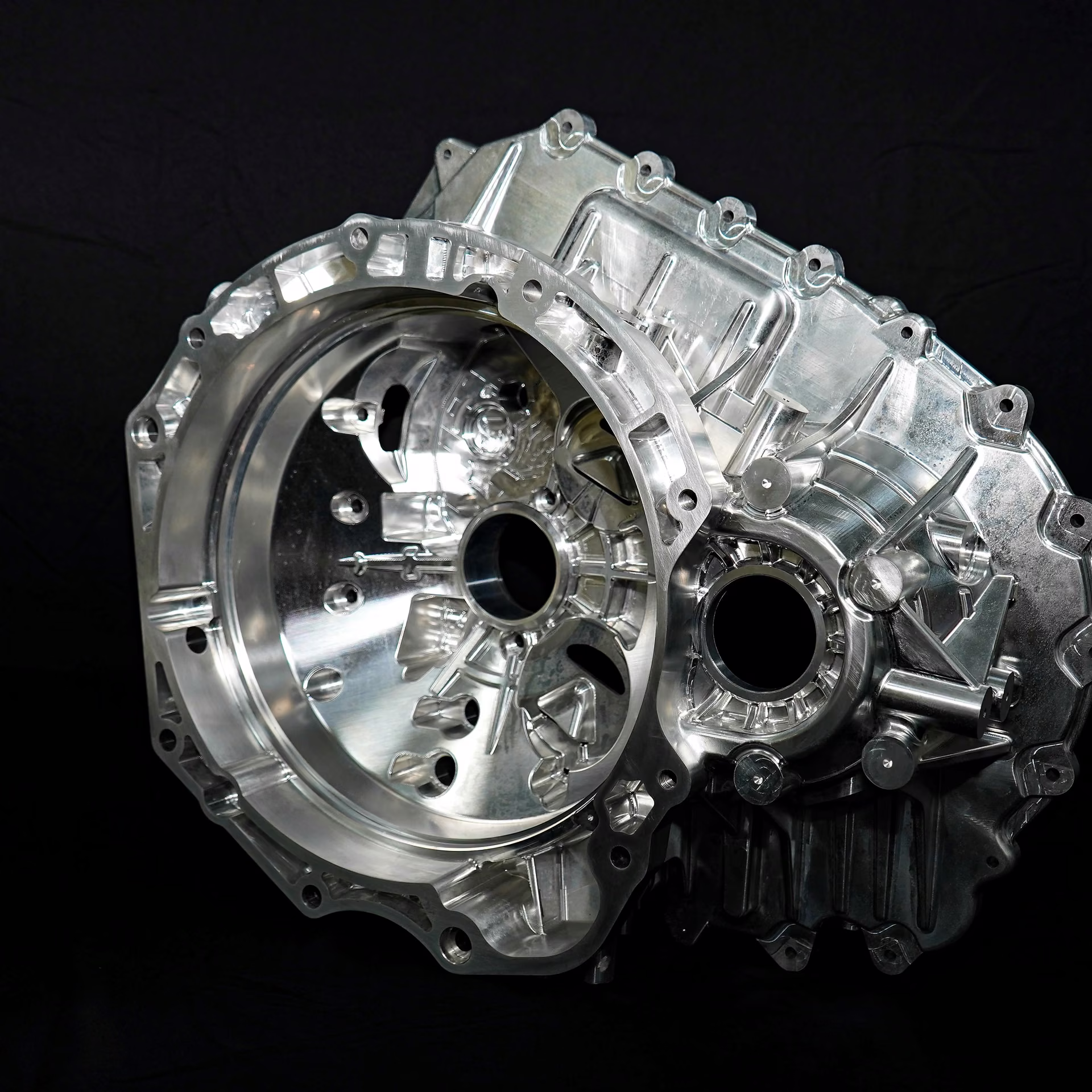 Machined aluminum automotive transmission housing with large bores, internal cavities, and perimeter mounting features.