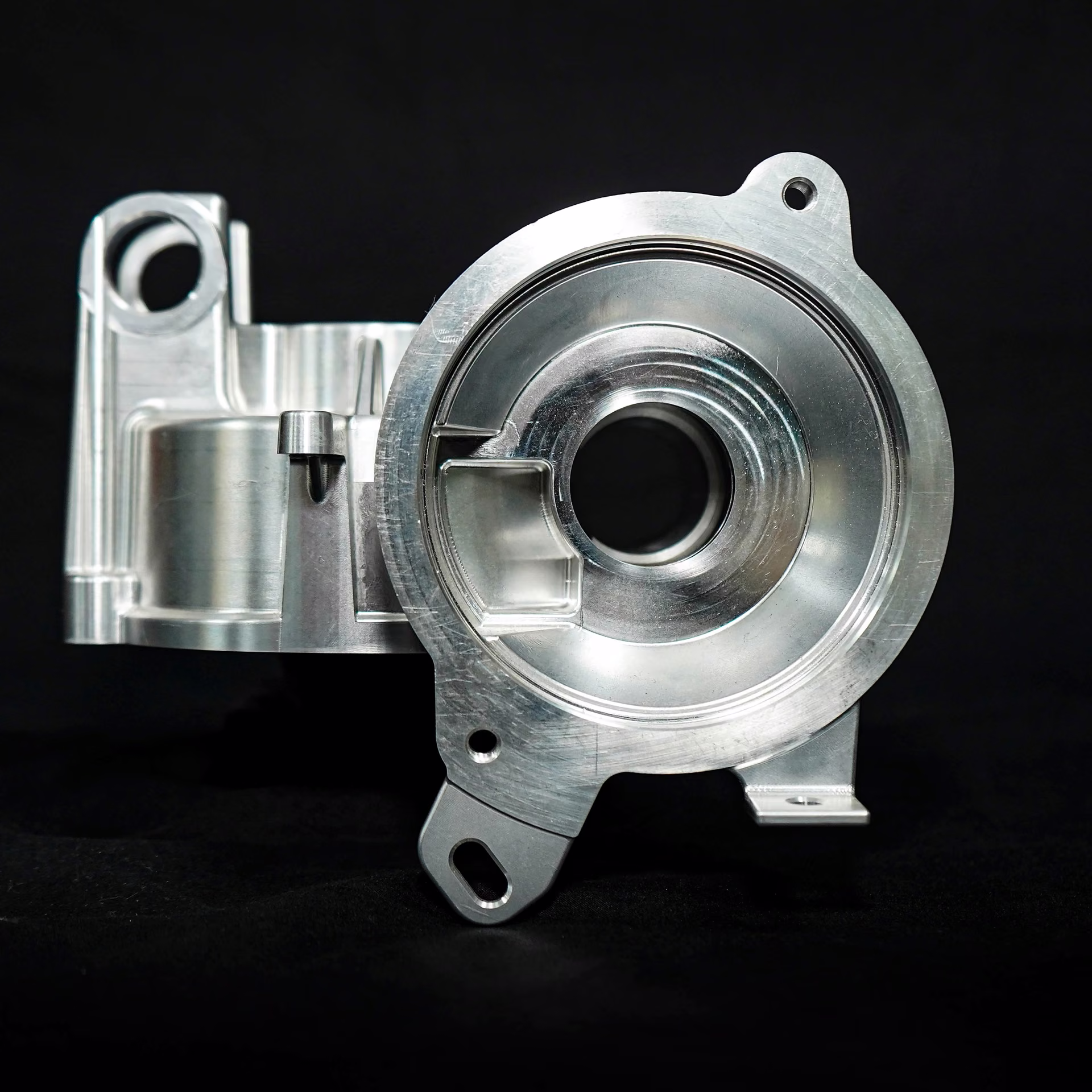 Machined aluminum turbocharger housing with a large central bore, flange surfaces, and mounting features.