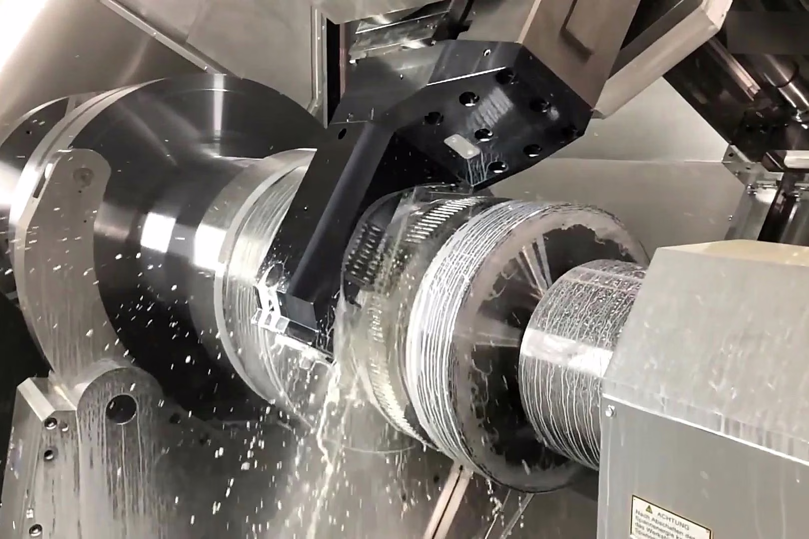 CNC mill-turn center machining a precision cylindrical metal shaft with a spindle chuck and live tooling