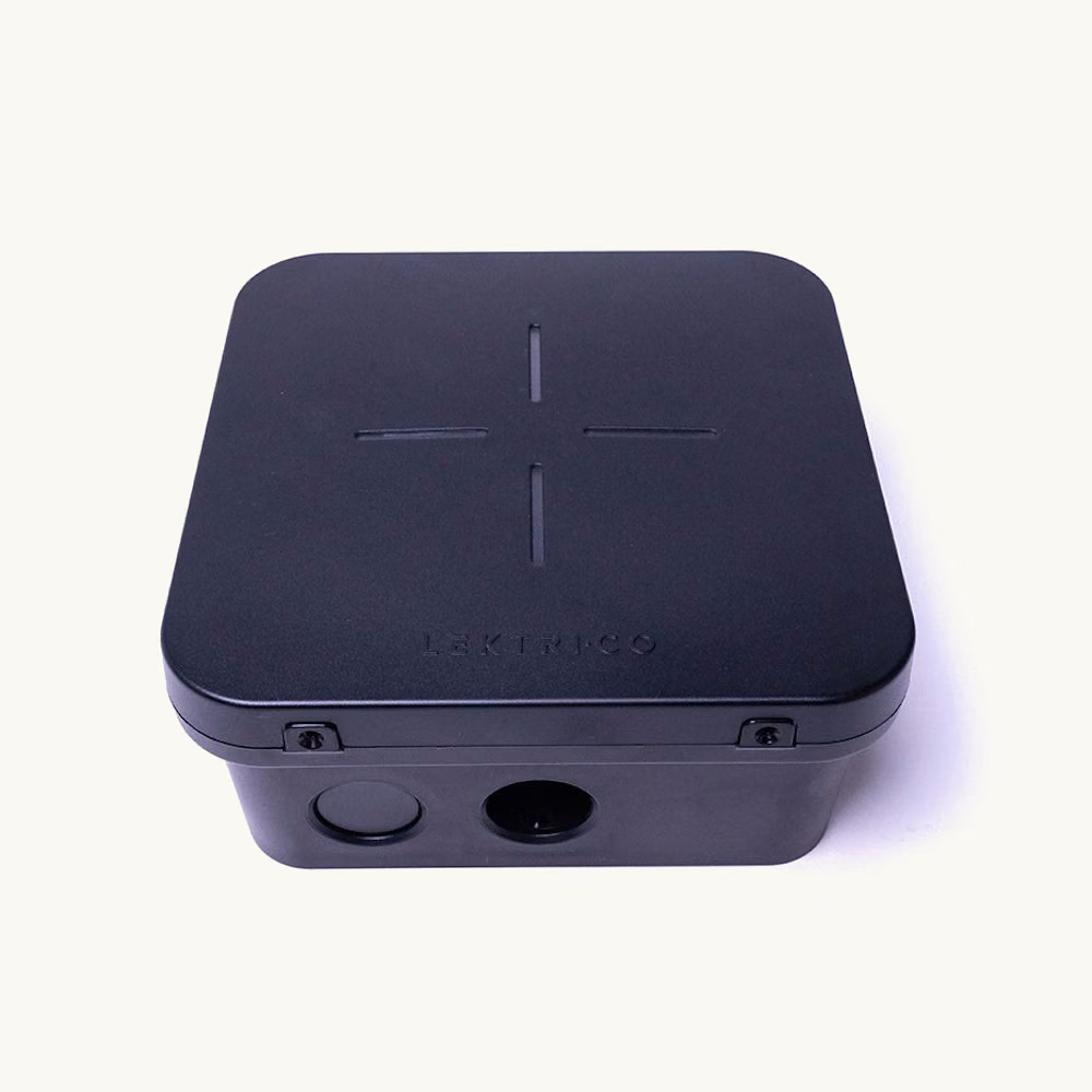 Compact black molded electronics housing with rounded corners, a smooth face, and side openings.
