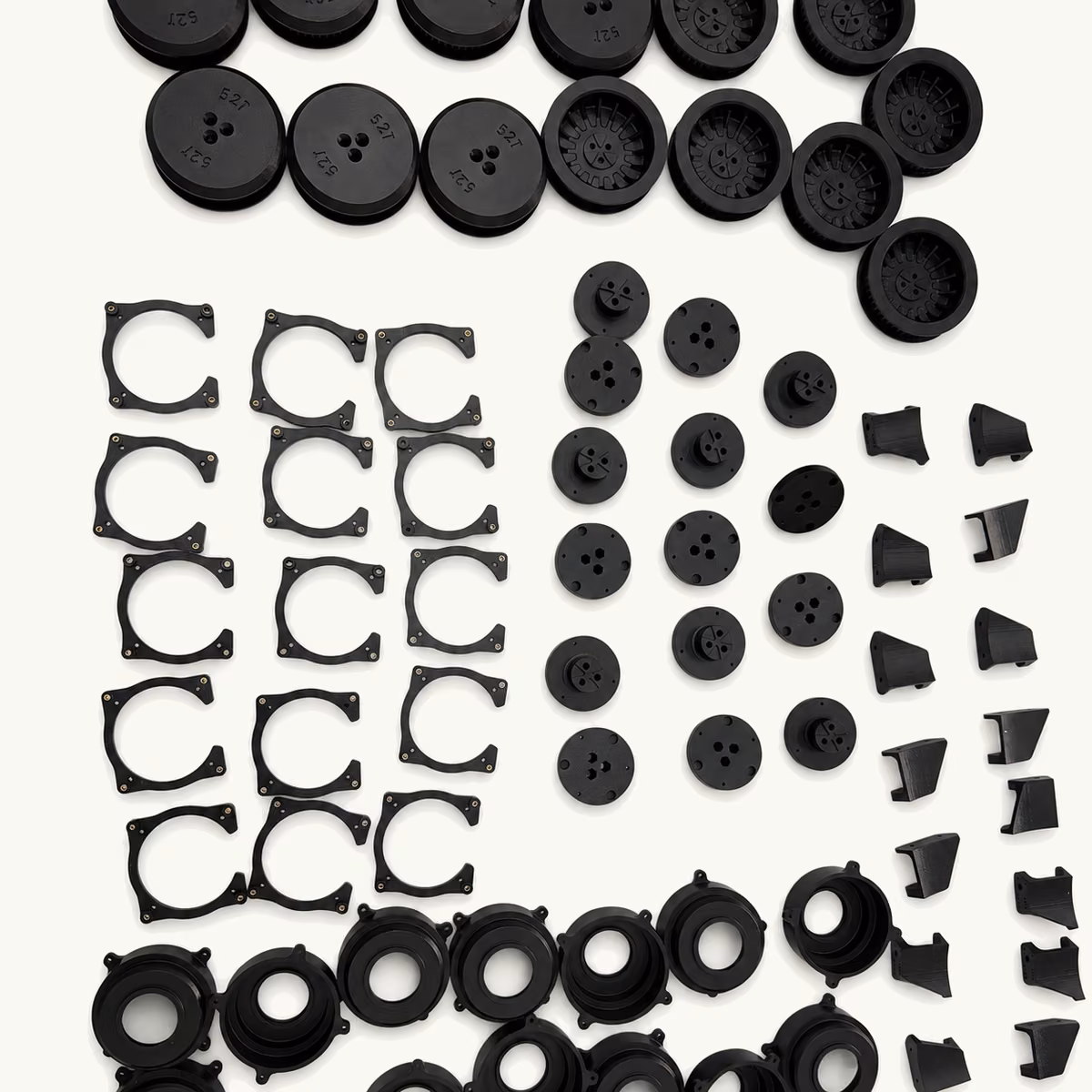 Organized batch of black molded gears, rings, spacers, clips, and small drive components.