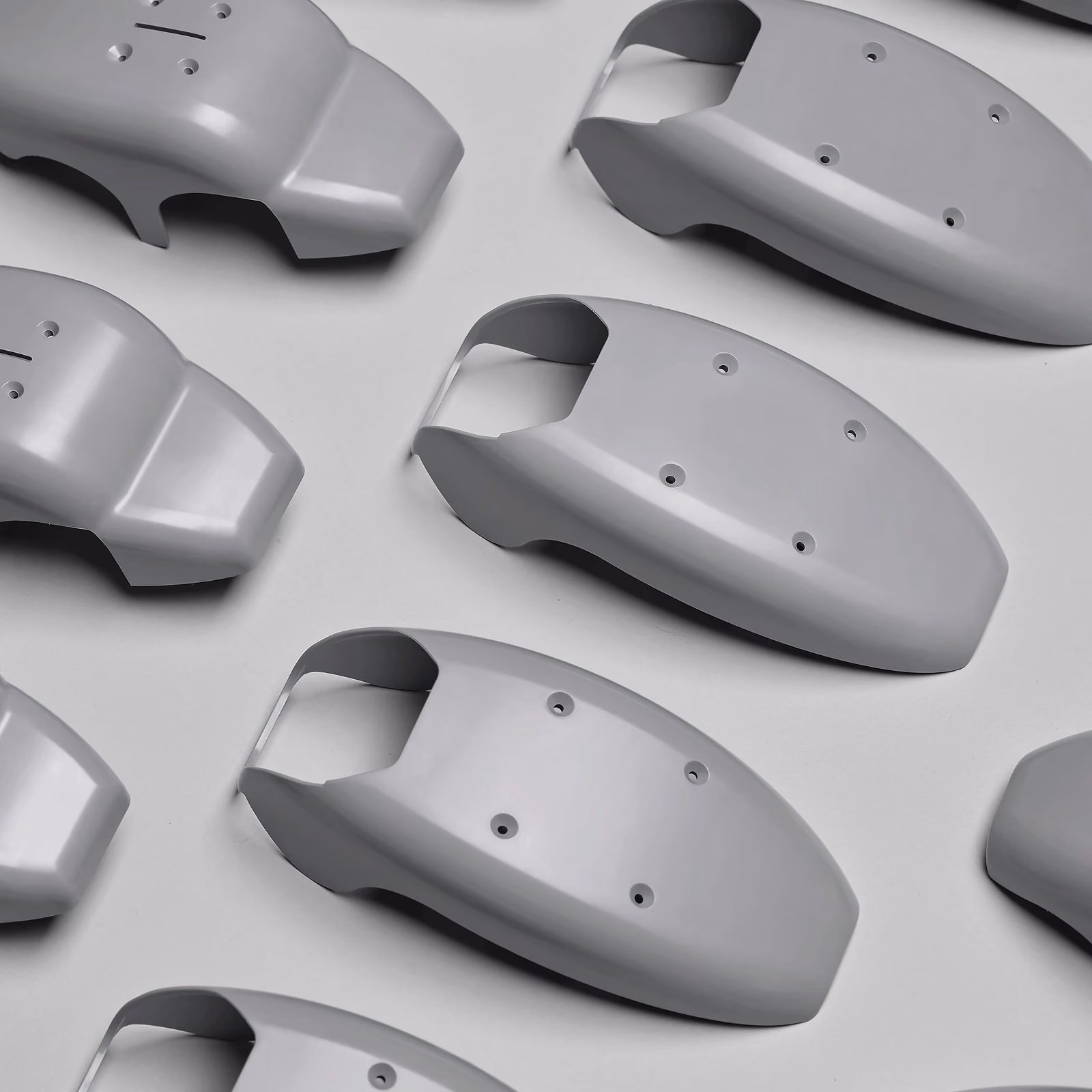 Batch of matching gray molded housing shells with rounded profiles and assembly openings.