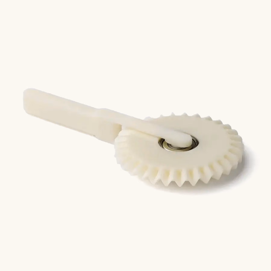 White molded polymer gear and lever component with an integrated metal pivot insert.