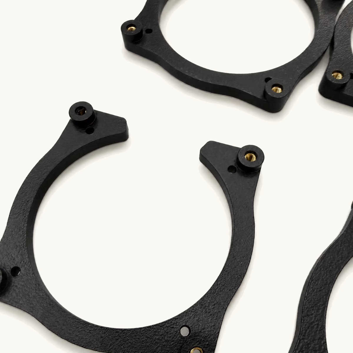 Black molded retaining rings and bracket components with reinforced profiles and mounting holes.