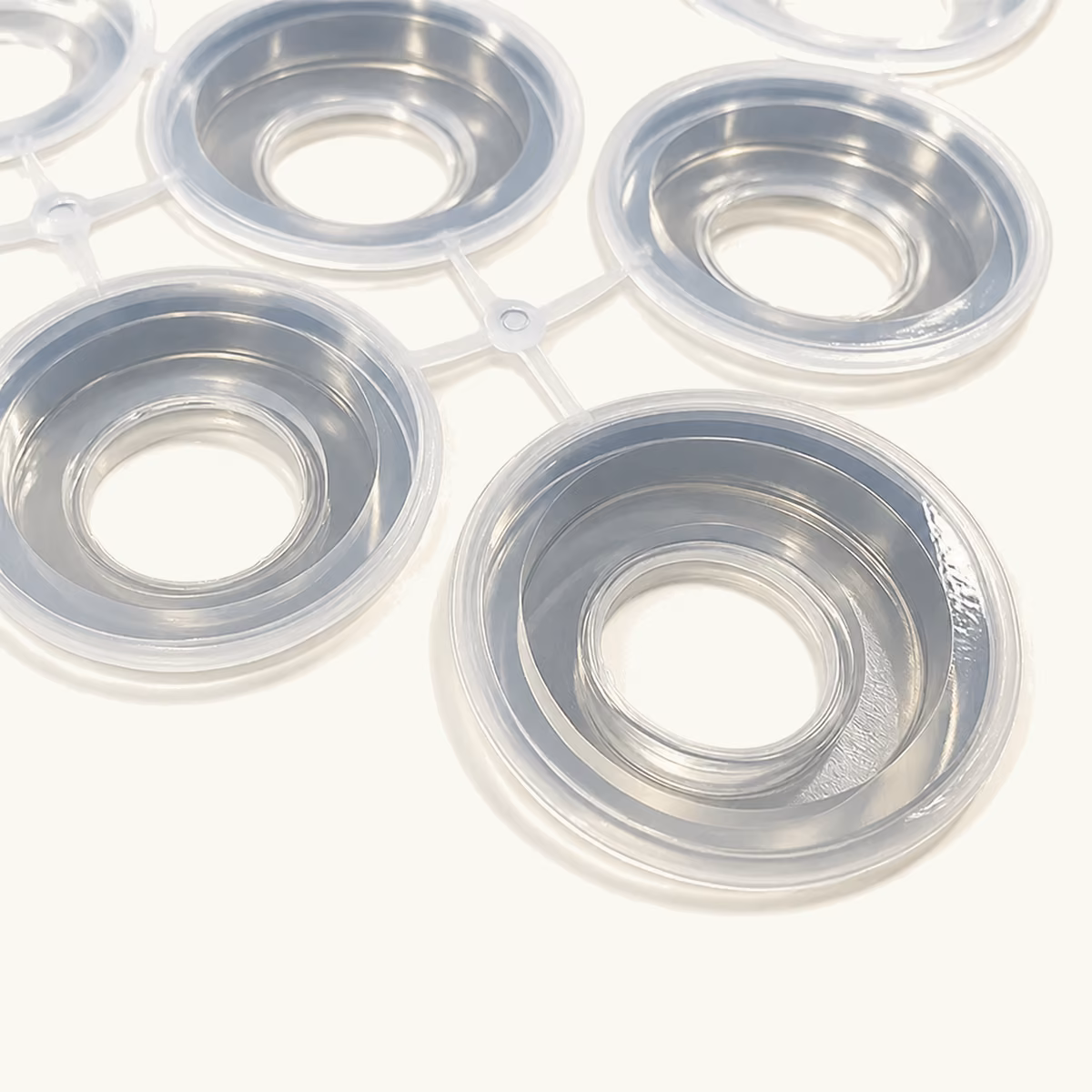 Set of translucent circular molded silicone seals arranged on a production surface.