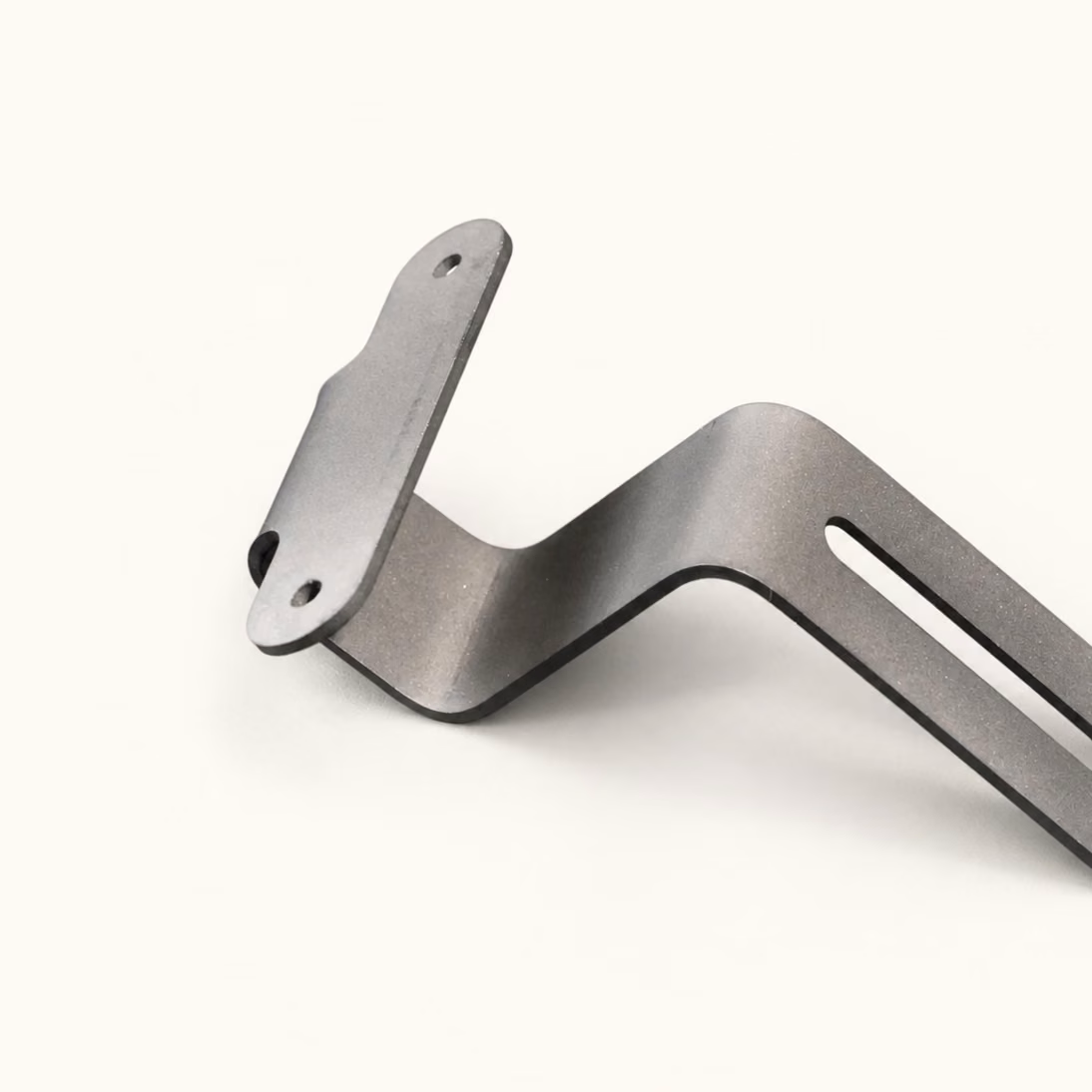 Silver bent sheet metal equipment bracket with an offset profile, mounting slots, and circular holes.