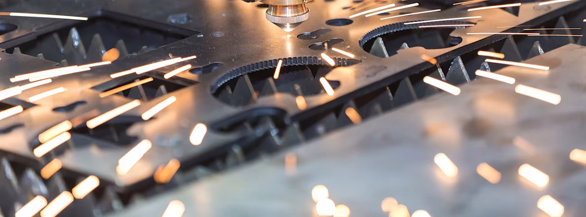 Fiber laser cutting detailed profiles from sheet metal with visible process sparks